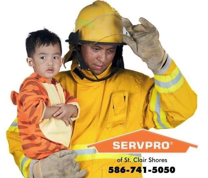 fire fighter holding a small boy in a tiger costume