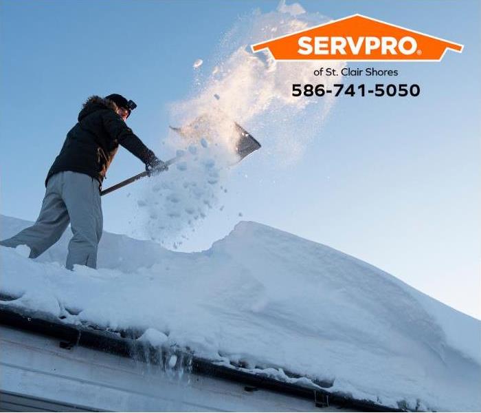 A person clears snow from a roof to prevent ice dam damage.
